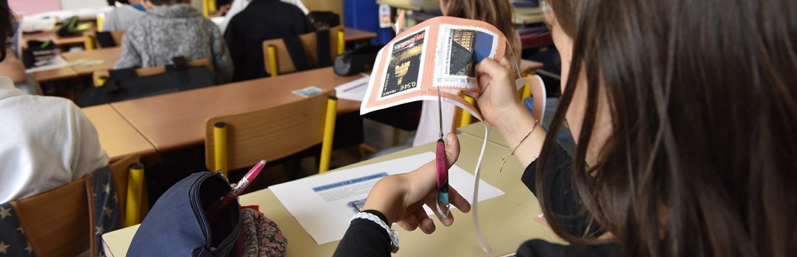 Atelier jeune public, petite fille découpant des timbres 