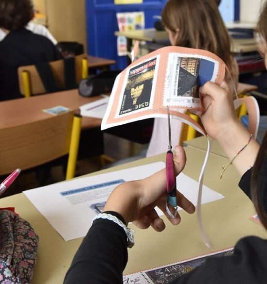 Atelier jeune public, petite fille découpant des timbres 